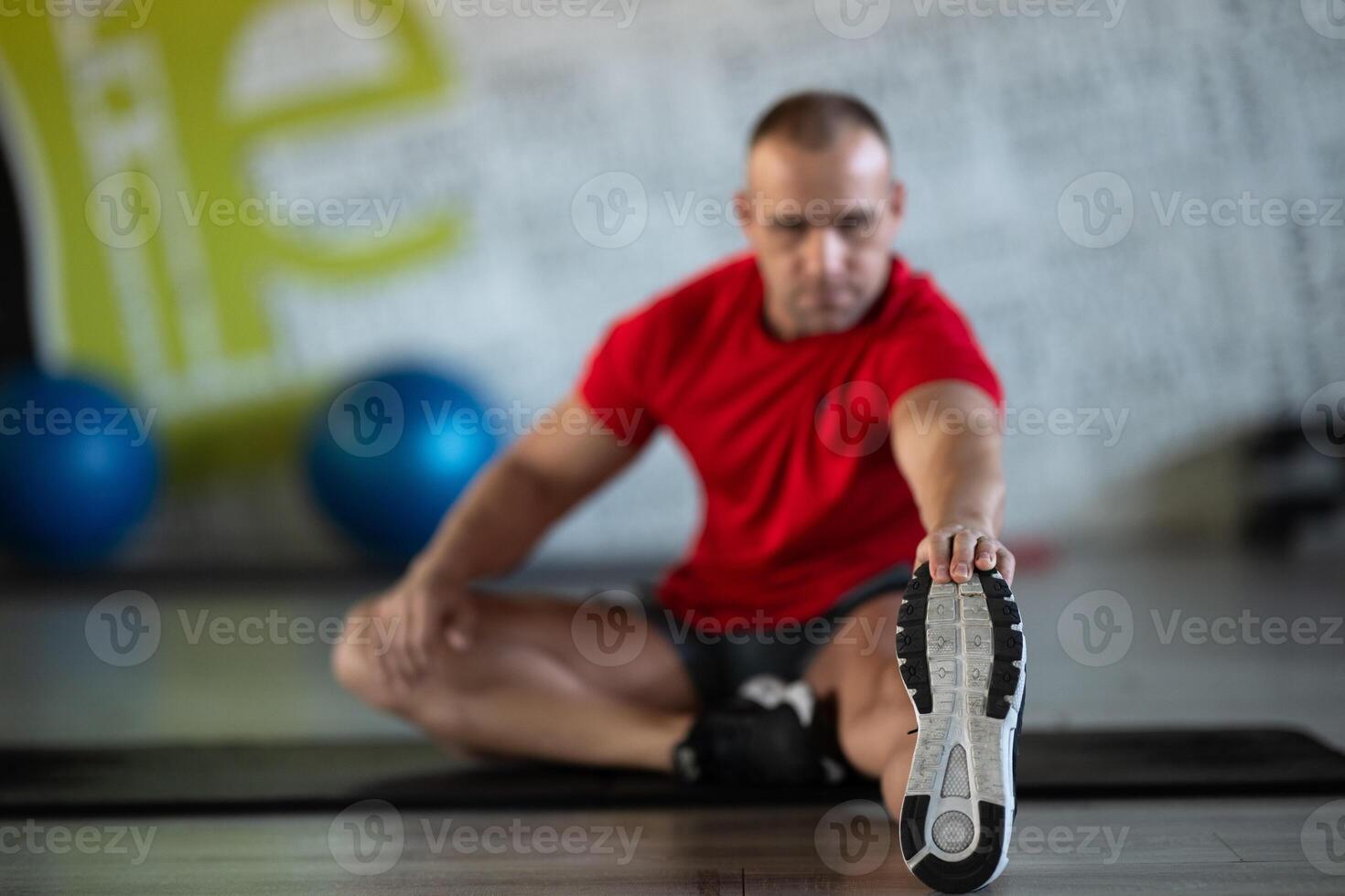A fitness man stretches in the gym after an intense workout, focusing on recovery and flexibility. photo