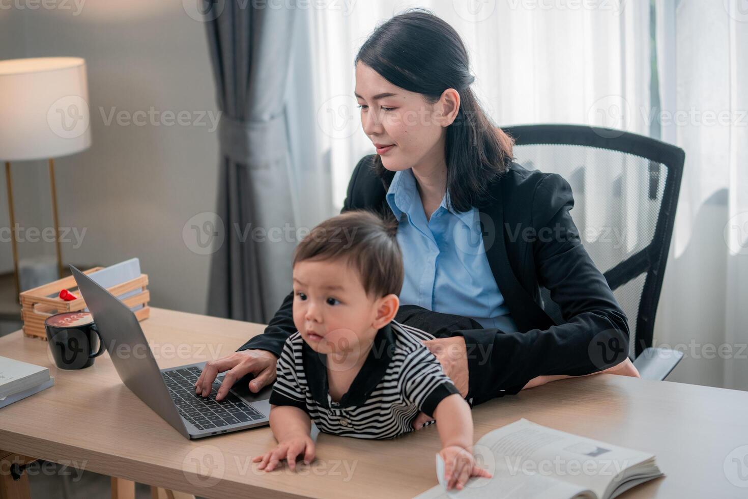 Working mother balances tasks with a child in a cozy home office environment during the day photo