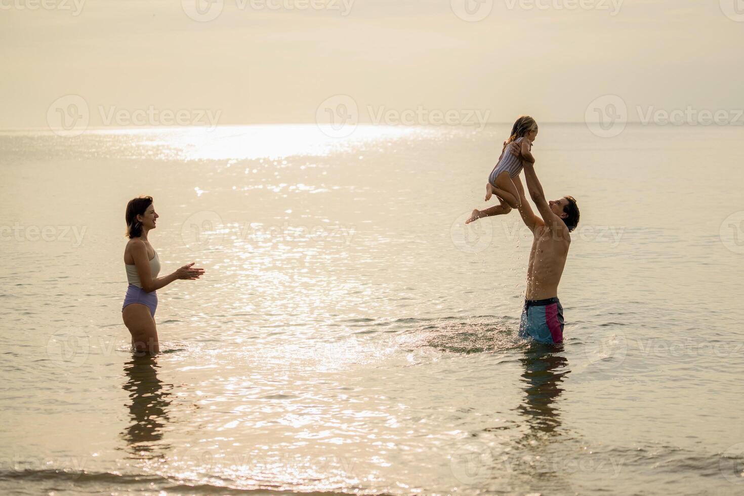 Family enjoys time at the beach during sunset, playing and bonding in the warm water with a joyful child photo