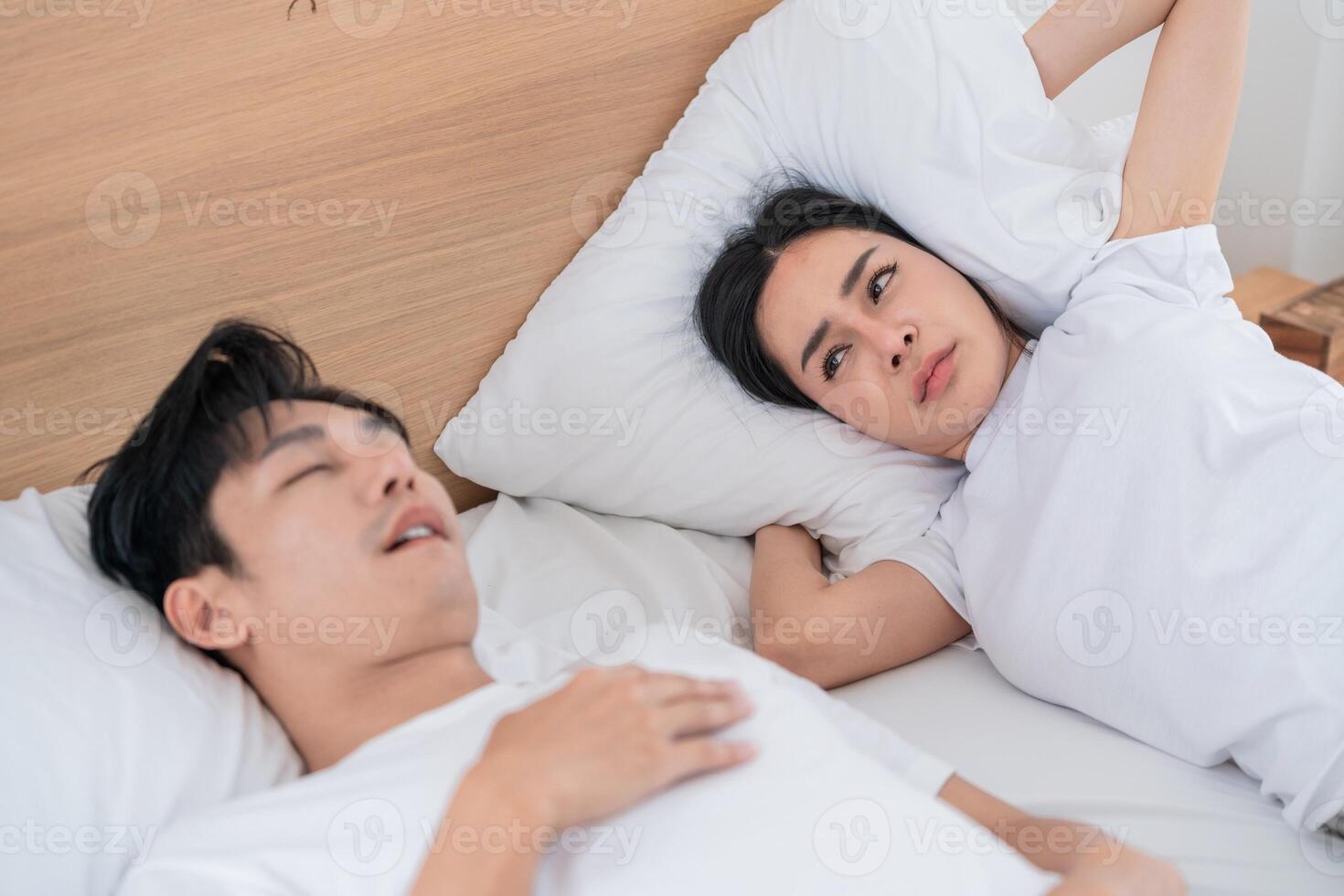 Couple in bed with one partner snoring, causing disruption at morning in a cozy bedroom setting photo