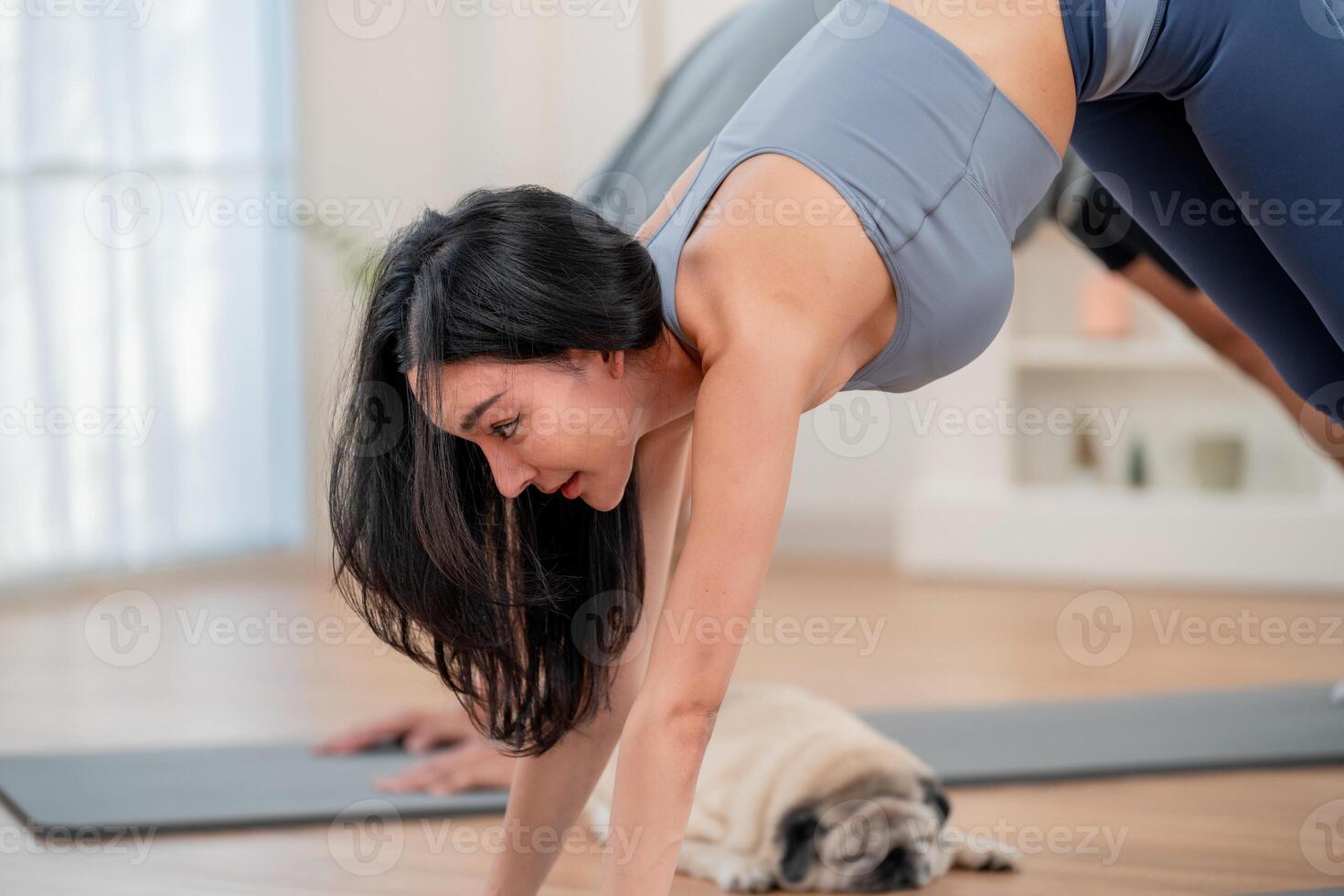 Woman practicing yoga in a well-lit studio with a dog nearby during a morning workout session photo
