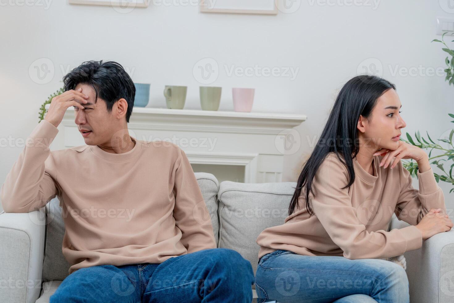 Couple sitting apart in a living room during an argument while feeling emotional and disconnected from each other photo