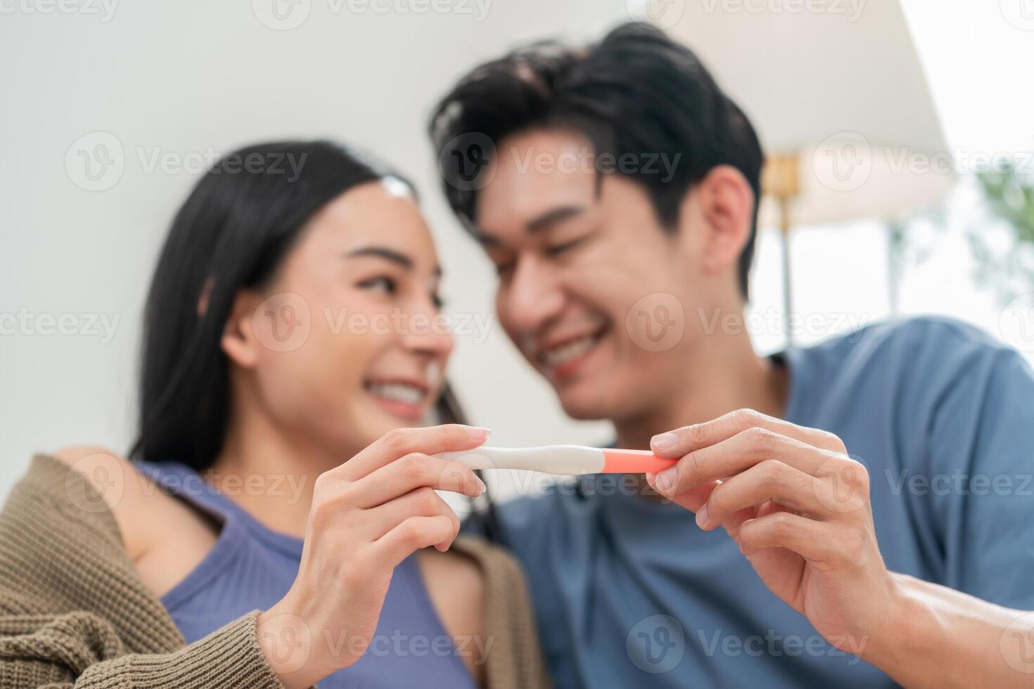 Happy couple celebrating positive pregnancy test at home in cozy living room photo