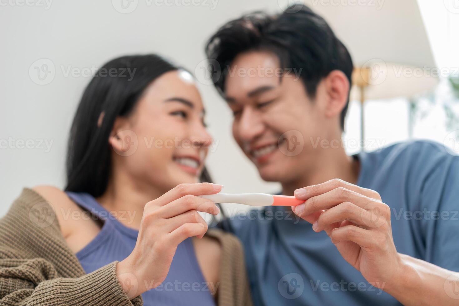 Couple excitedly sharing pregnancy test results in a cozy indoor setting while celebrating new beginnings photo