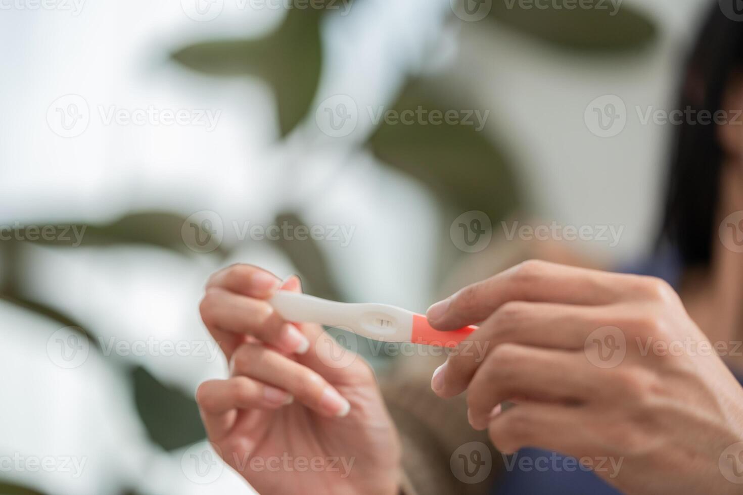 Woman holds a pregnancy test in a well-lit room while expressing emotions of anticipation and hope photo