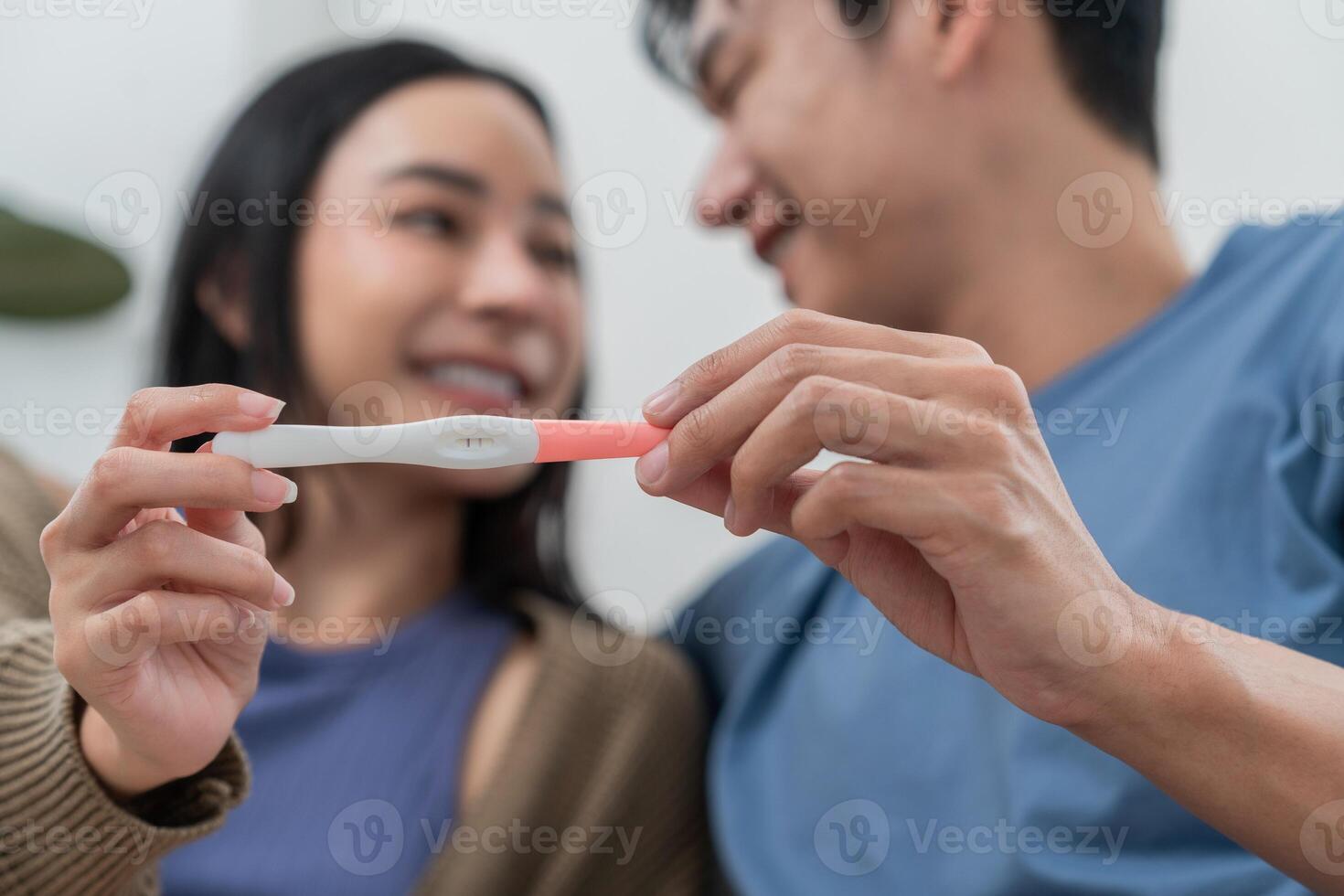 A happy couple sits together with a pug resting on their laps, showcasing an ultrasound image with smiles. The warm atmosphere captures their excitement about expecting a baby. photo