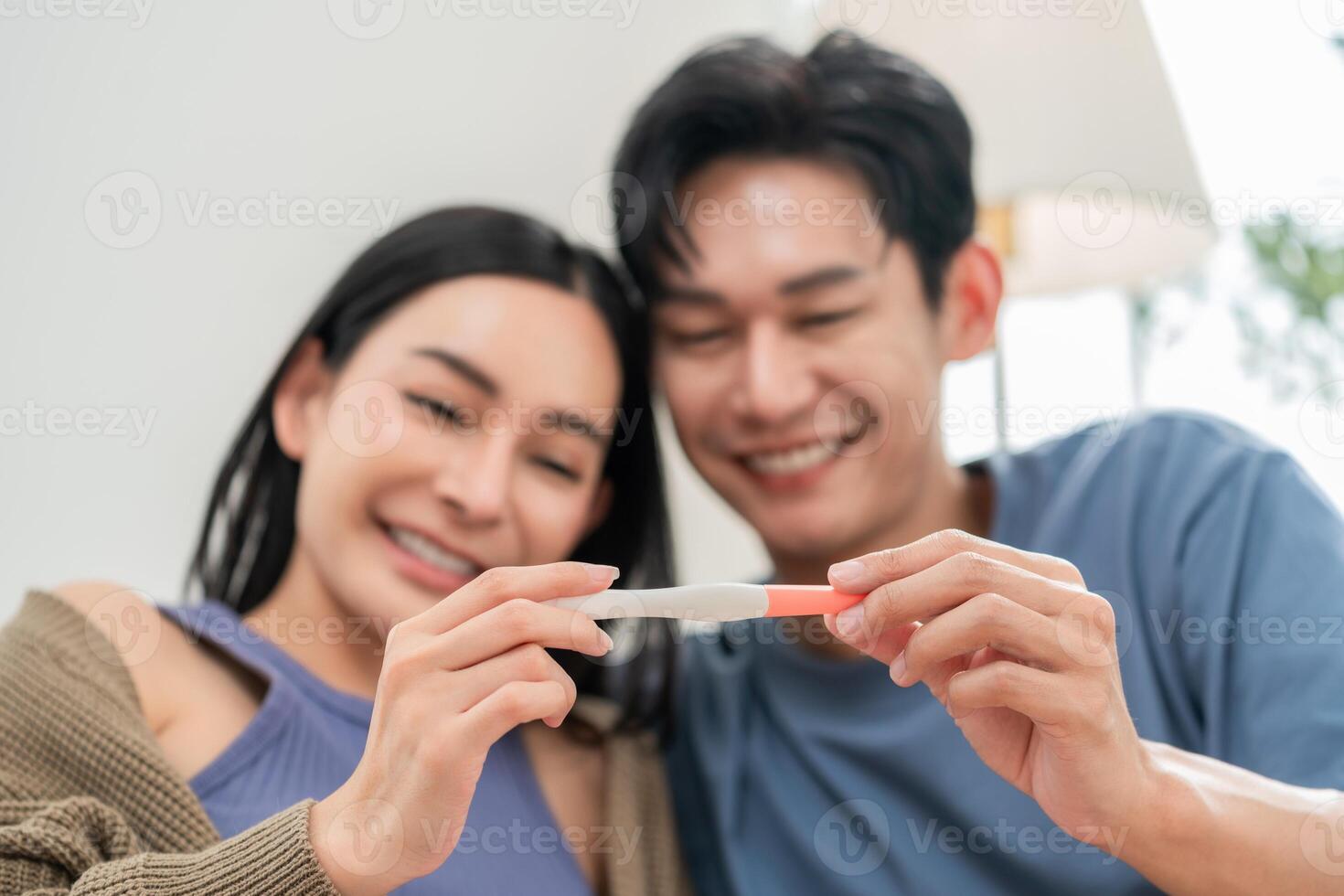 Couple joyfully sharing news of pregnancy with a positive test result in a cozy setting photo