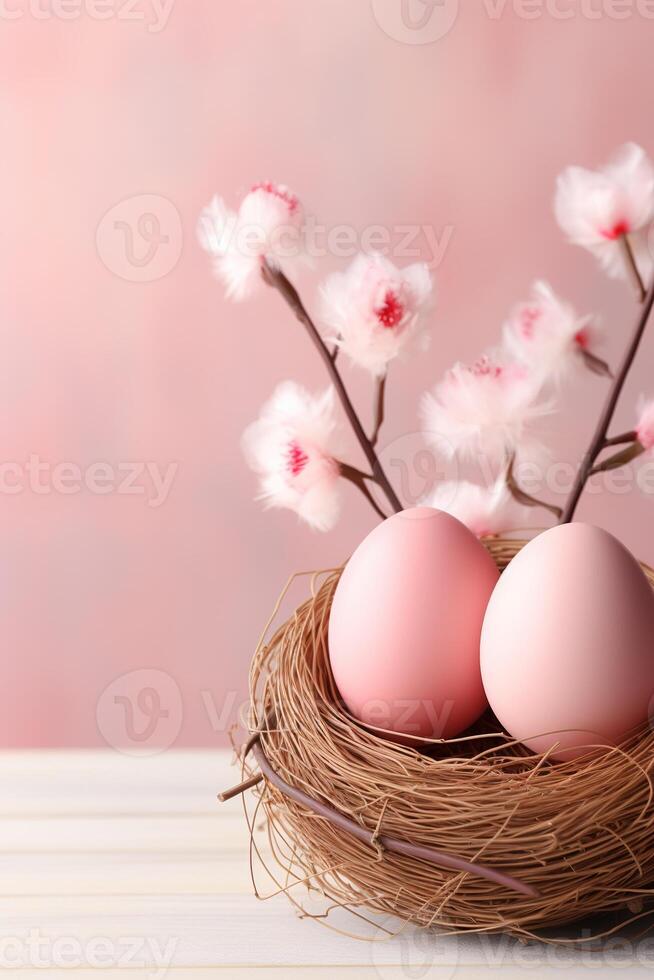 vertical composition small straw bird nest of pink eggs with delicate flowers on pink background photo