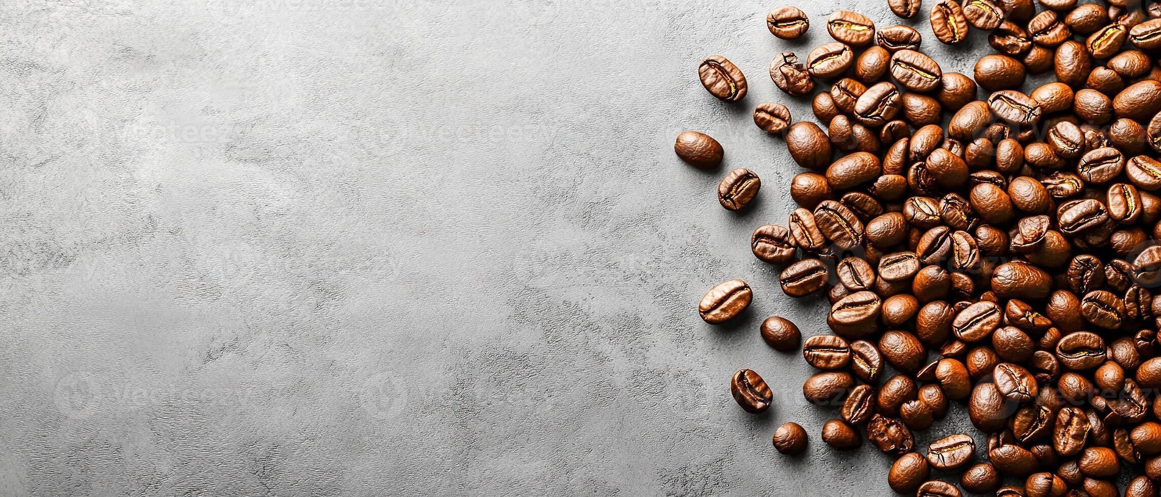 Scattered Roasted Coffee Beans on a Smooth Grey Textured Background with Copy Space photo