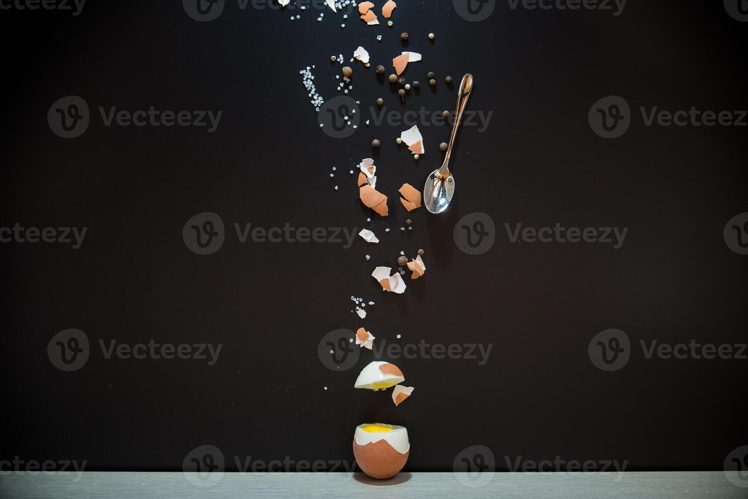 Boiled egg with spices and shell on black background photo