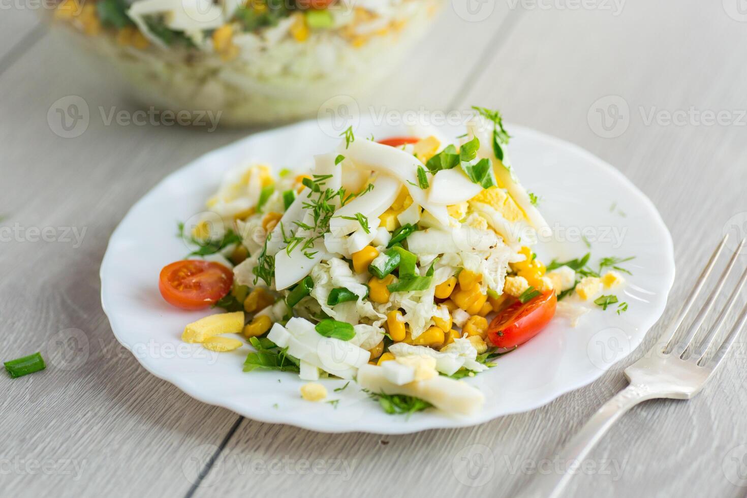 Diet salad with cabbage.Chinese cabbage salad with squid, eggs, tomatoes and other vegetables photo