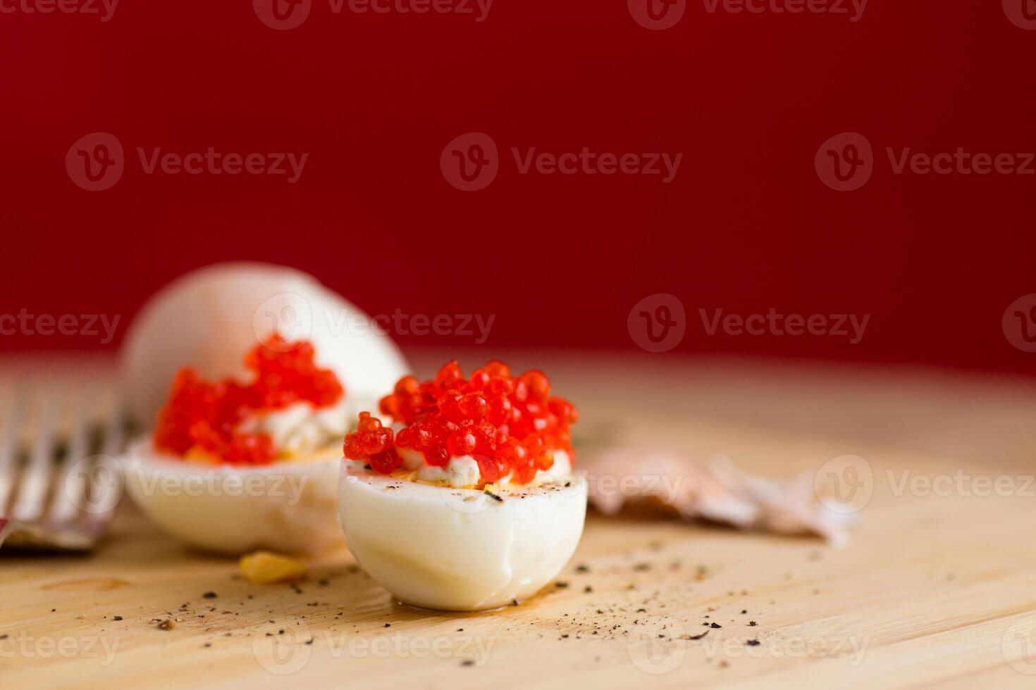 boiled eggs with red caviar on a red background photo