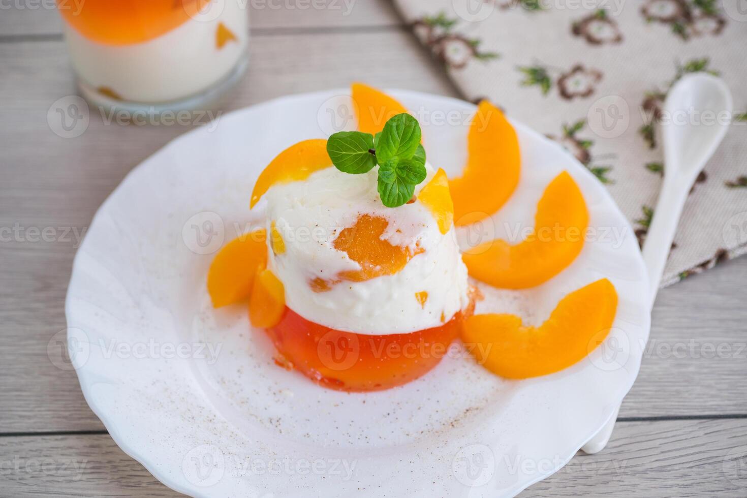 Pieces of canned peaches inside multilayer jelly on wooden table photo