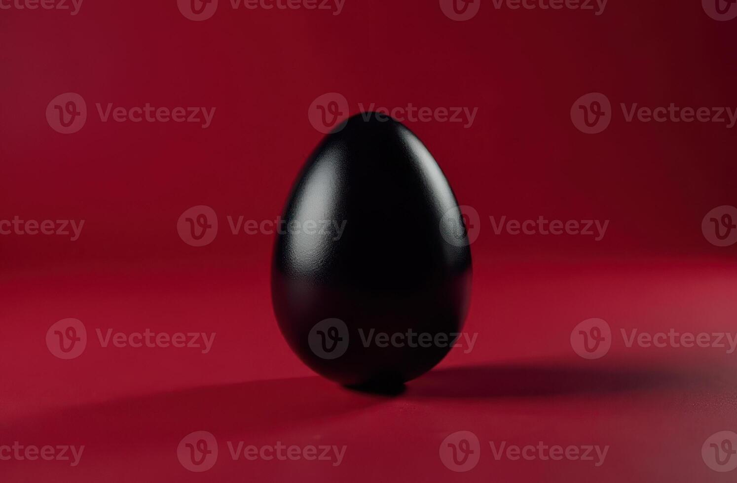 Reflective black egg on a deep red background, modern and artistic Easter look photo