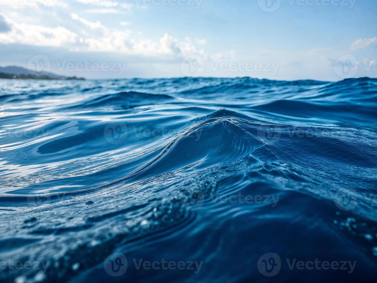 Calm ocean waves gently ripple under a clear blue sky during midday light photo