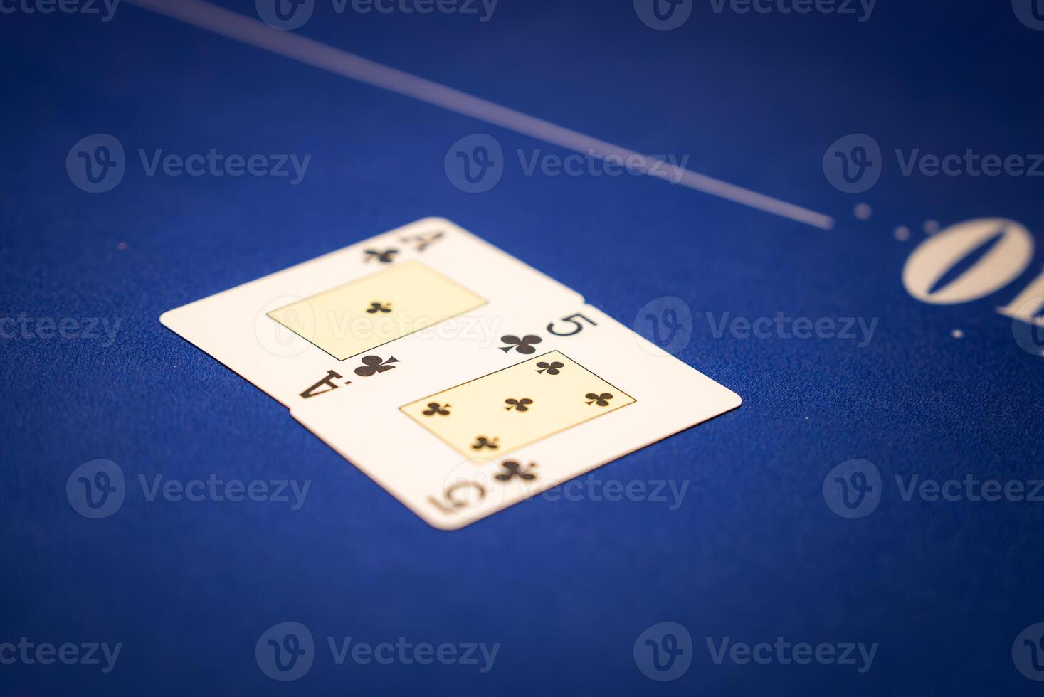 Two playing cards, the 10 of clubs and queen of clubs, rest on a blue poker table with white markings, showcasing a formal gaming setup. photo