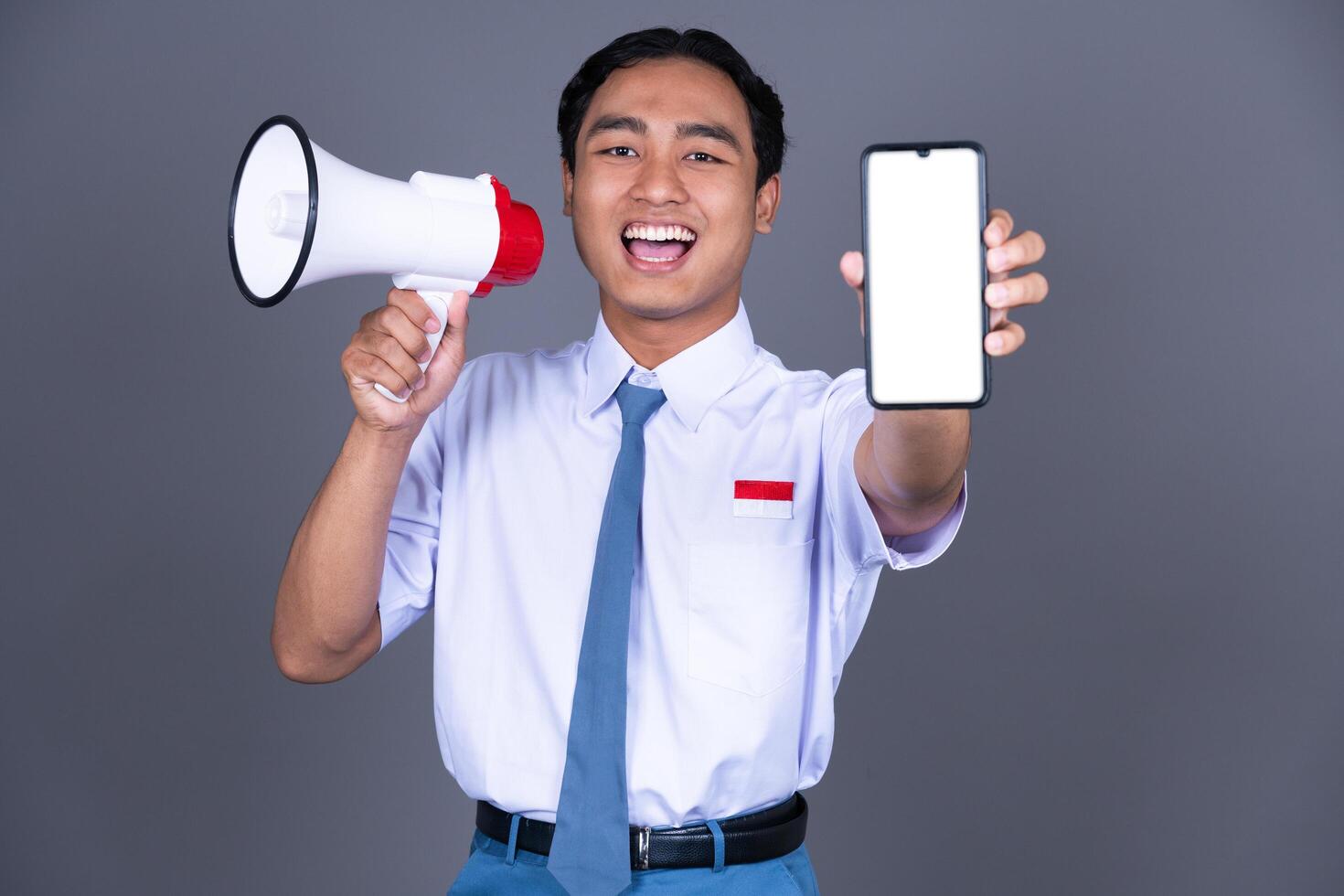 Indonesian Male High School Students in Uniform with Megaphone And Showing Smartphone photo