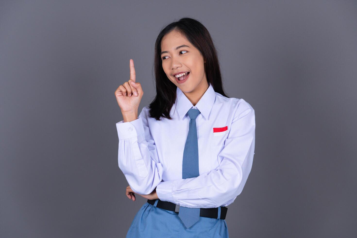 Indonesian Female High School Student in Uniform Smiling While Pointing Finger photo