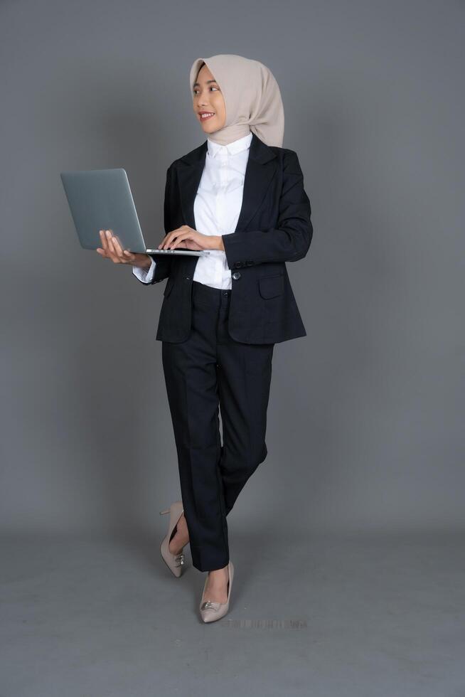 Full Body Portrait of Young Female Office Worker in a Hijab Holding Laptop Isolated Background photo