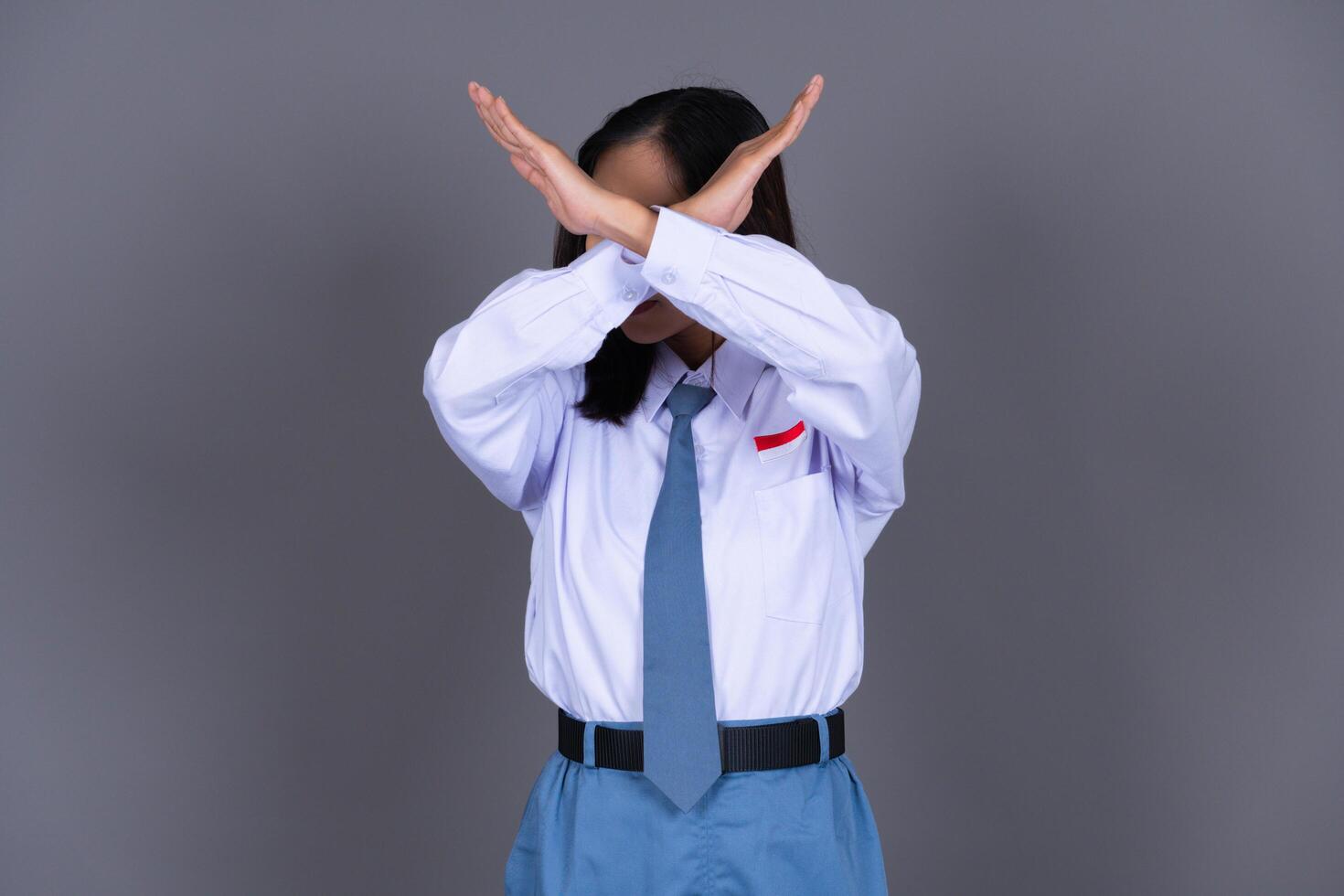 Indonesian Female High School Student in Uniform Showing Cross Sign Saying No photo