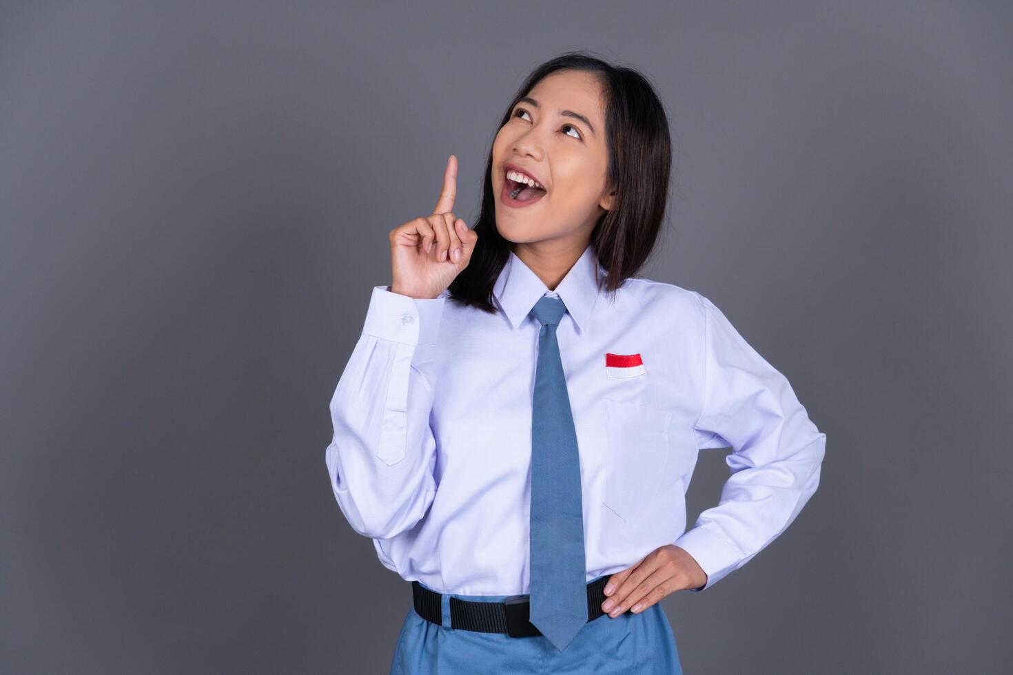 Indonesian Female High School Student in Uniform Smiling While Pointing Finger Background photo