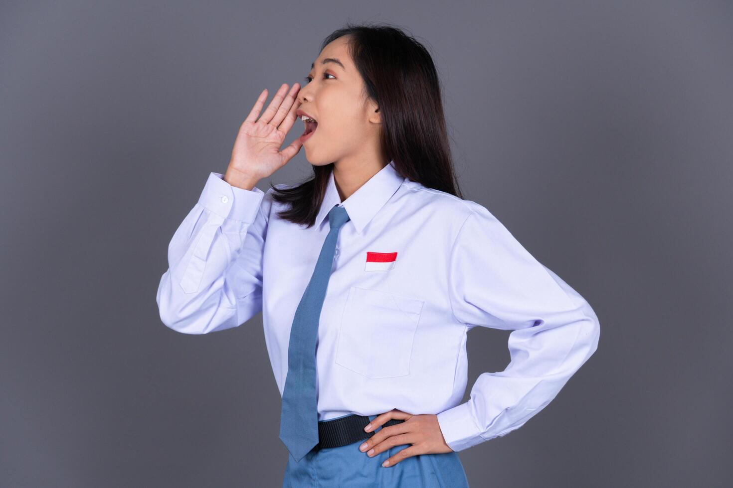 Indonesian Female High School Student in Uniform Shouting with Hand on Mouth photo