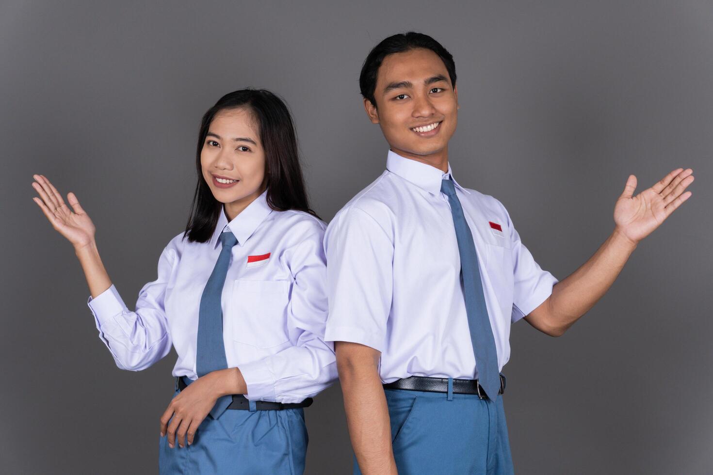Indonesian Male and Female High School Student in Uniform Presenting Gesture Isolated Background photo