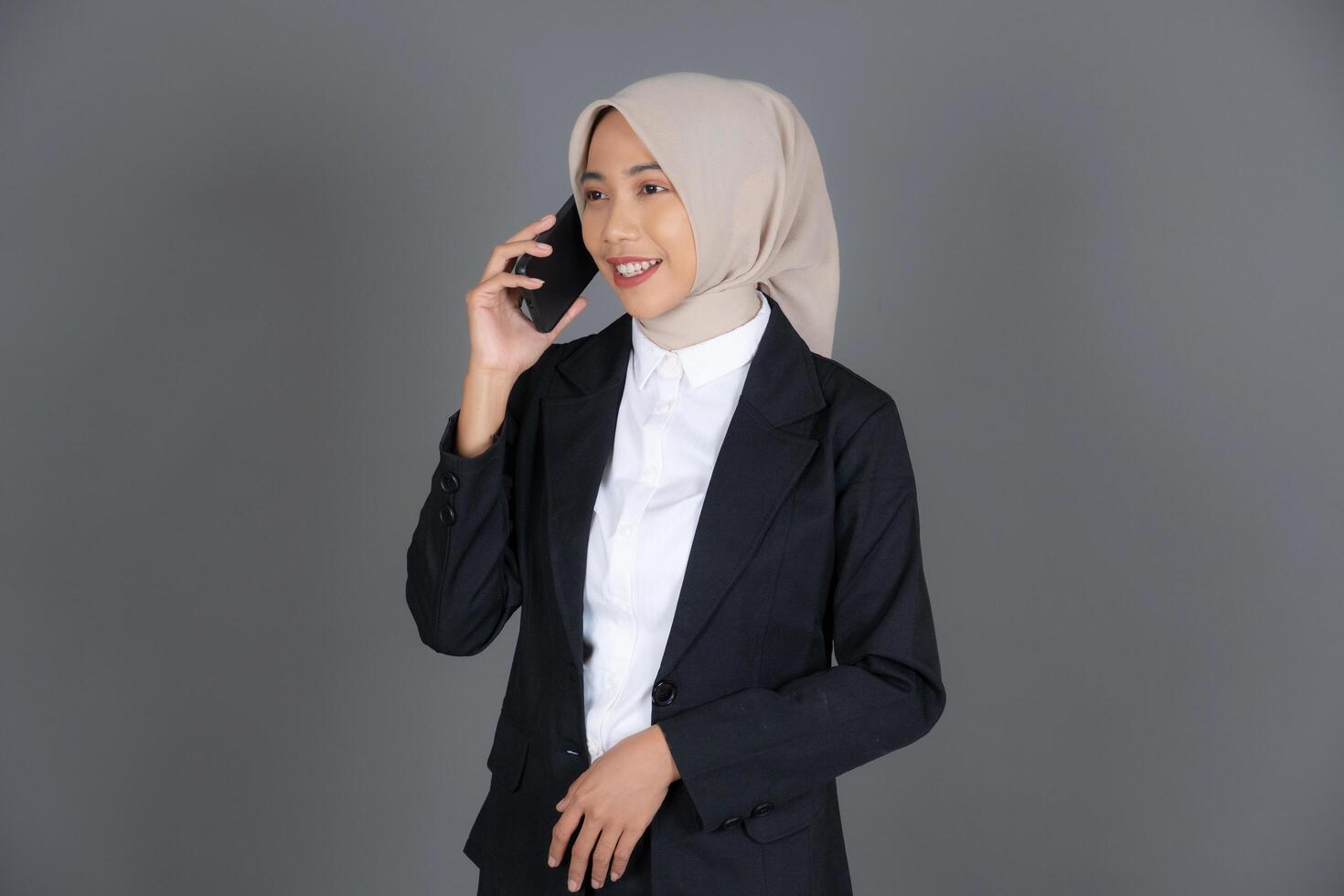 Portrait of Young Woman Office Worker in a Hijab Holding Mobile Phone Isolated Background photo