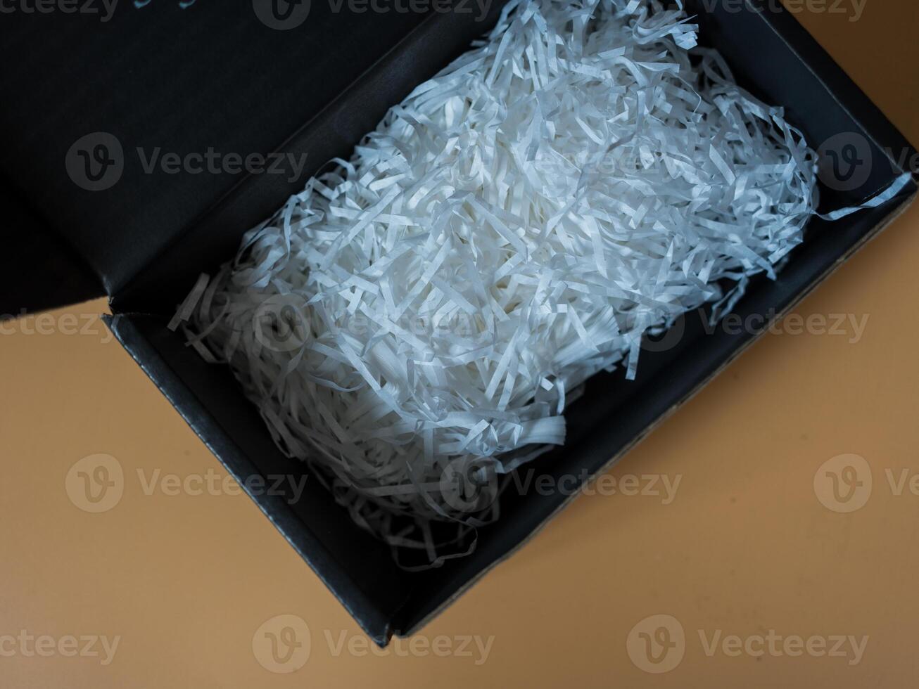 Opened cardboard box overflowing with vibrant white crinkled paper filler photo