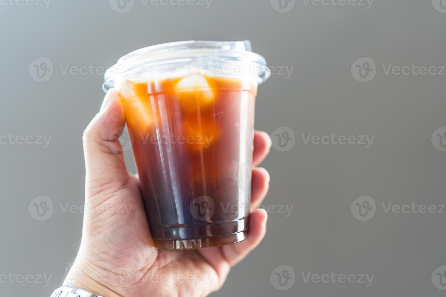 Take away plastic cup of iced black coffee or Americano in hand photo