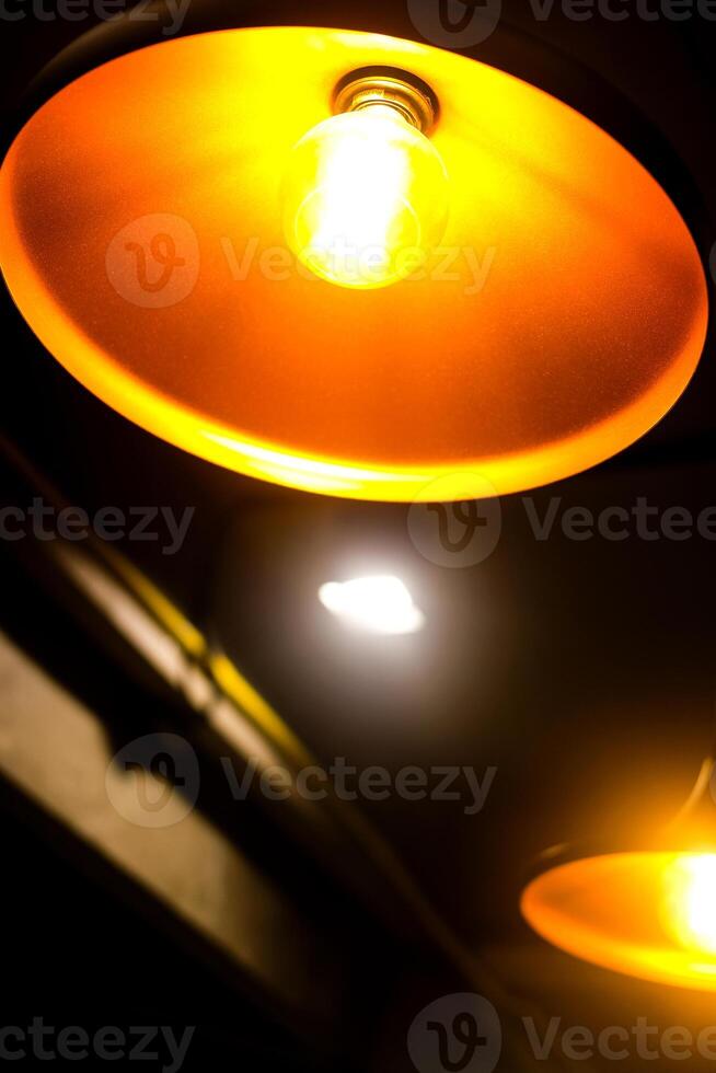 Glowing light bulb hangs from a chain against, radiating warm orange light. photo