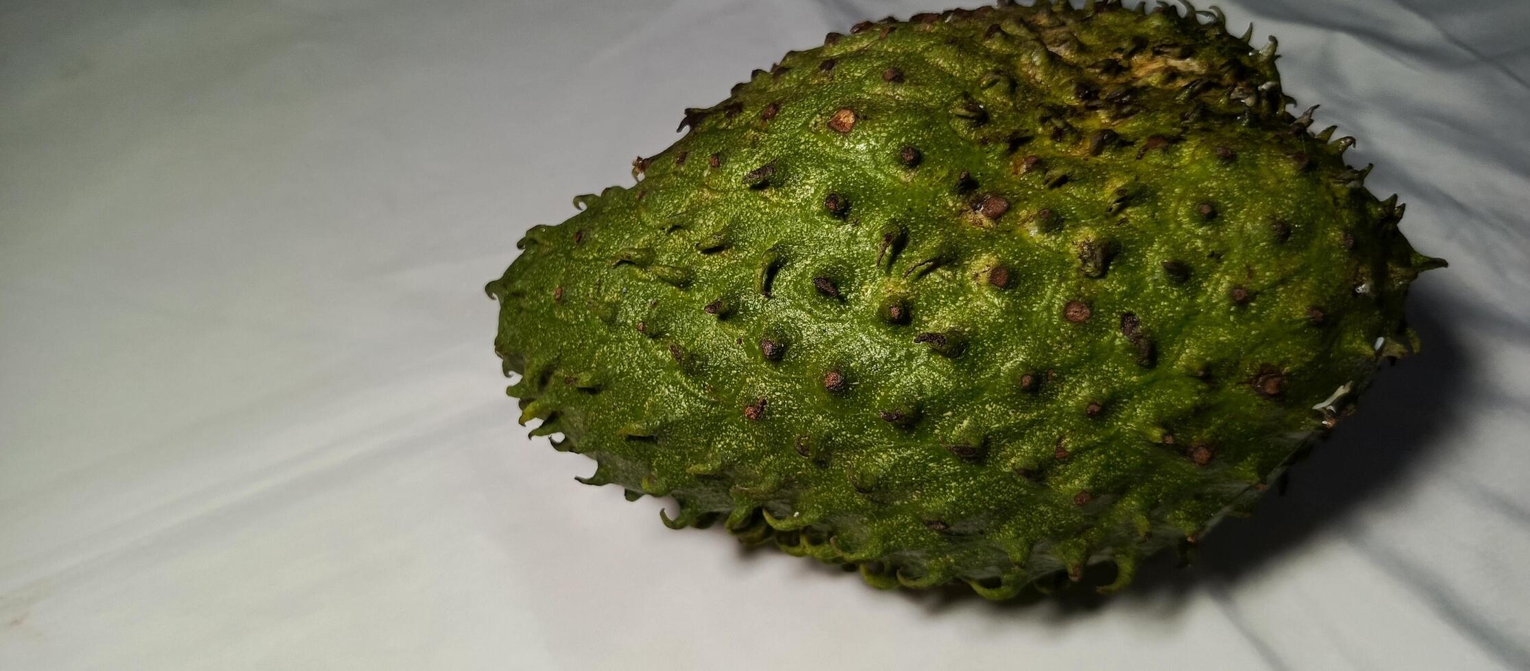 The large soursop fruit is green on a white background photo