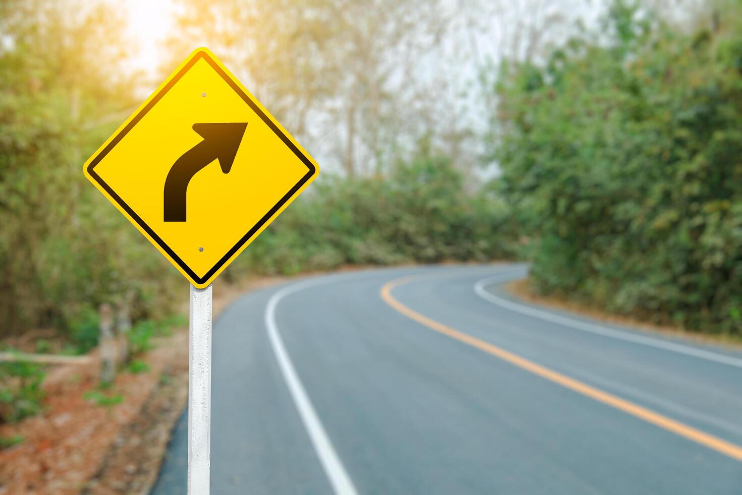 A right turn arrow with a blurred curved road in the background, safety direction and movement warn. photo