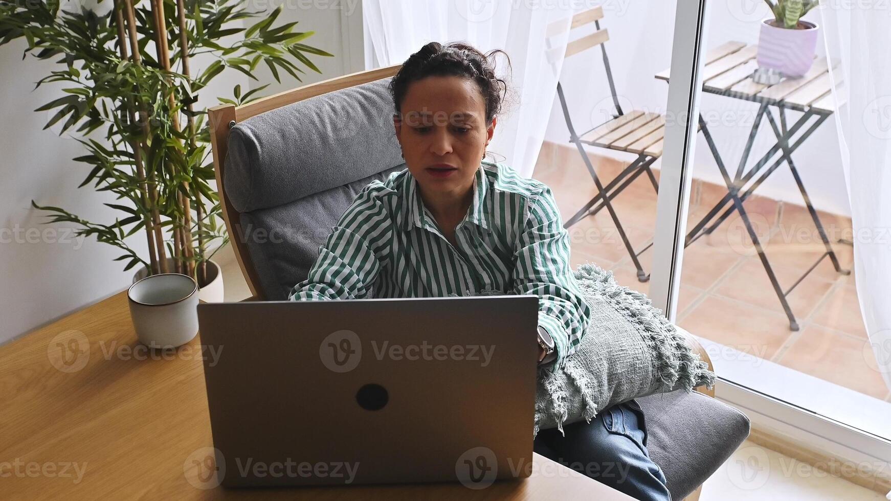 A young woman, entrepreneur freelancer, works remotely in her cozy home office, balancing lifestyle with online duties, featuring natural lighting and a serene environment. photo