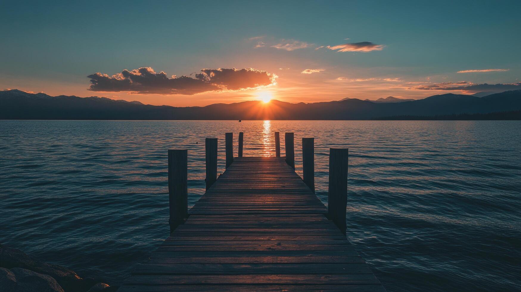 wooden pier extending over calm lake at sunset with reflection photo
