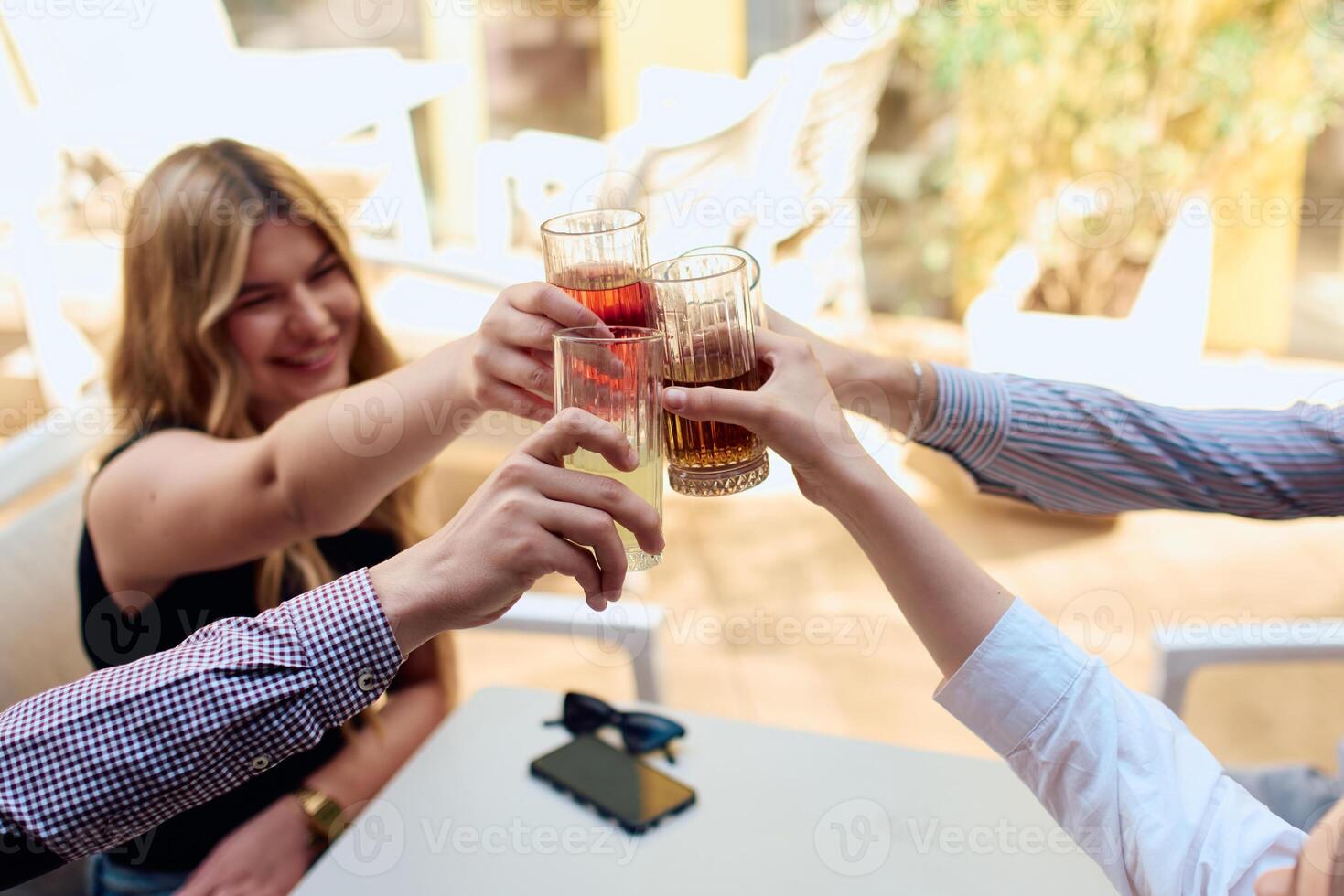 A diverse group of friends sitting together in a cozy cafe, smiling and raising their glasses in a joyful toast, celebrating friendship and good times photo