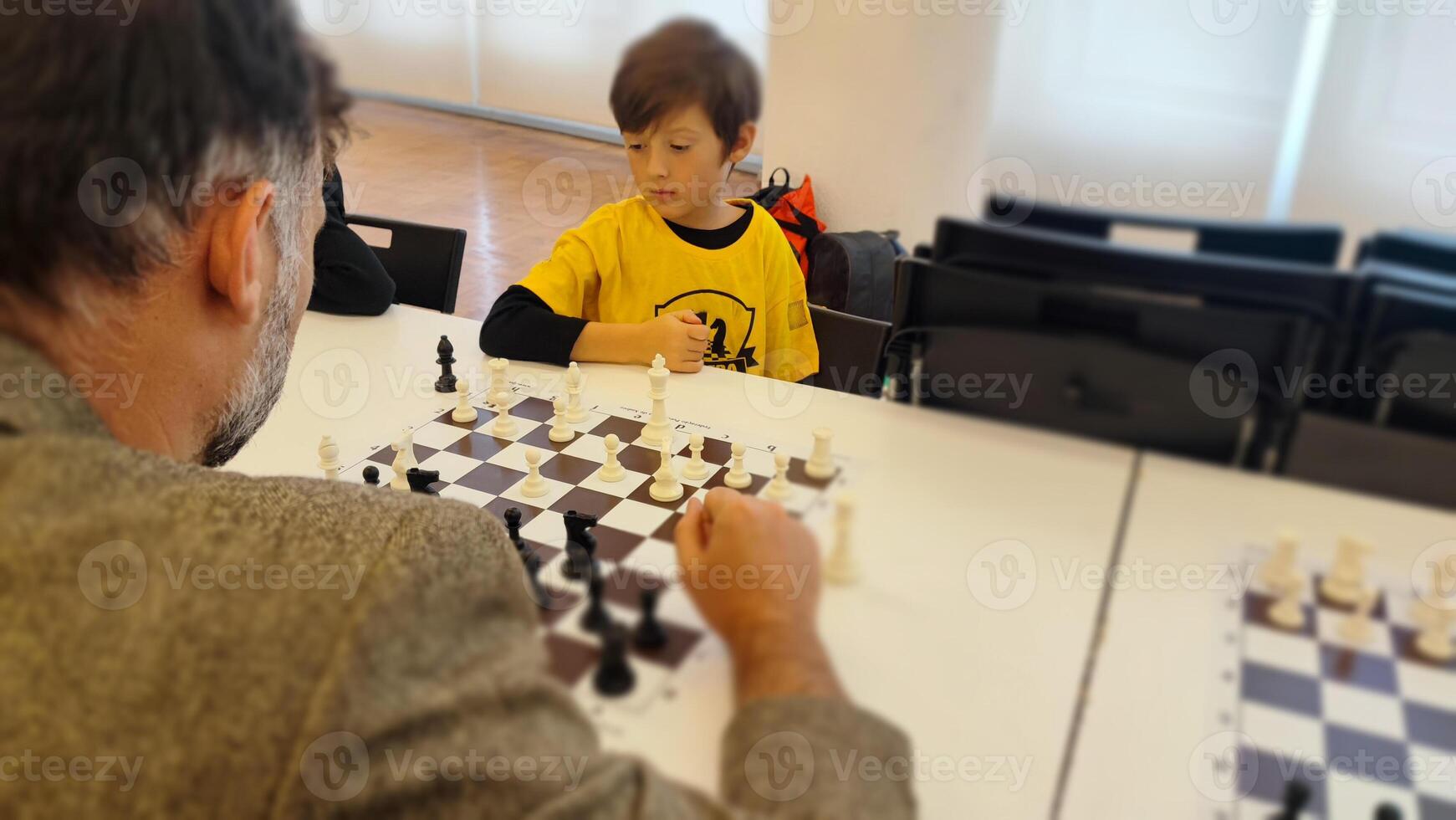 chessplayer. Clever junior school age boy playing chess with dad planning gambit moving black piece on chessboard. Preteen son engaged in brain developing activity enjoy board game with father photo