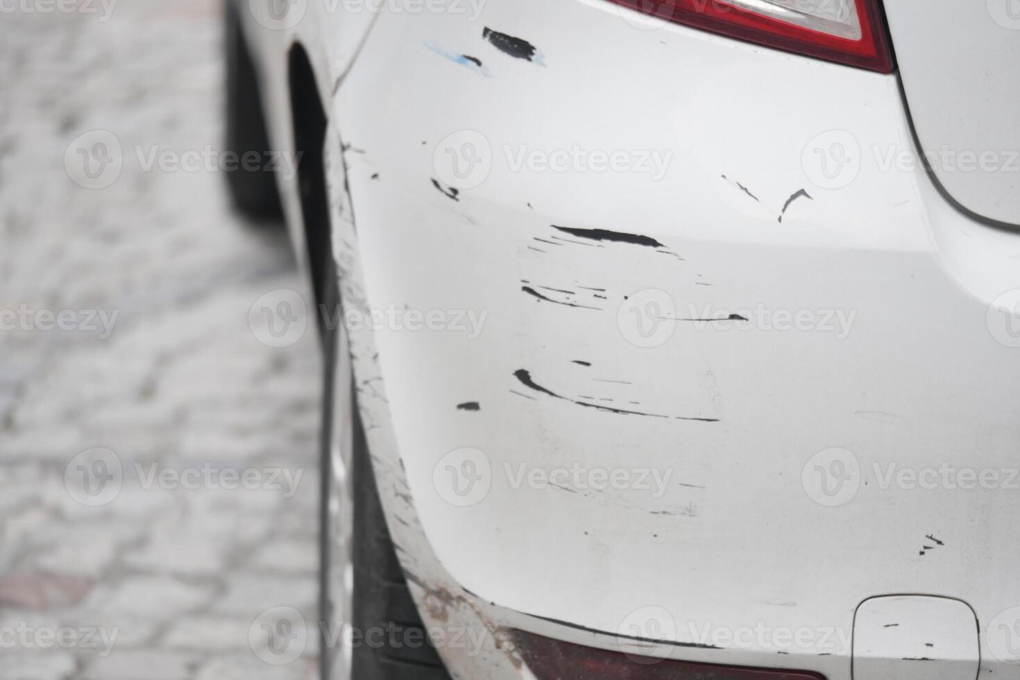 Car with visible scratches parked on a cobblestone street photo