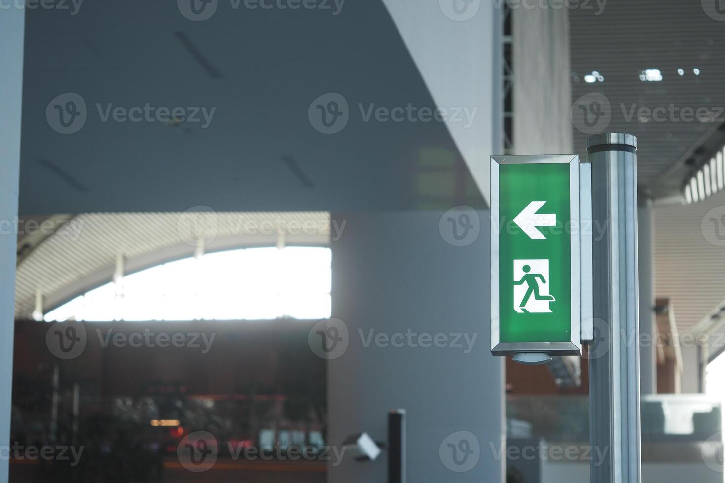Emergency exit sign directing towards the left in a modern building photo
