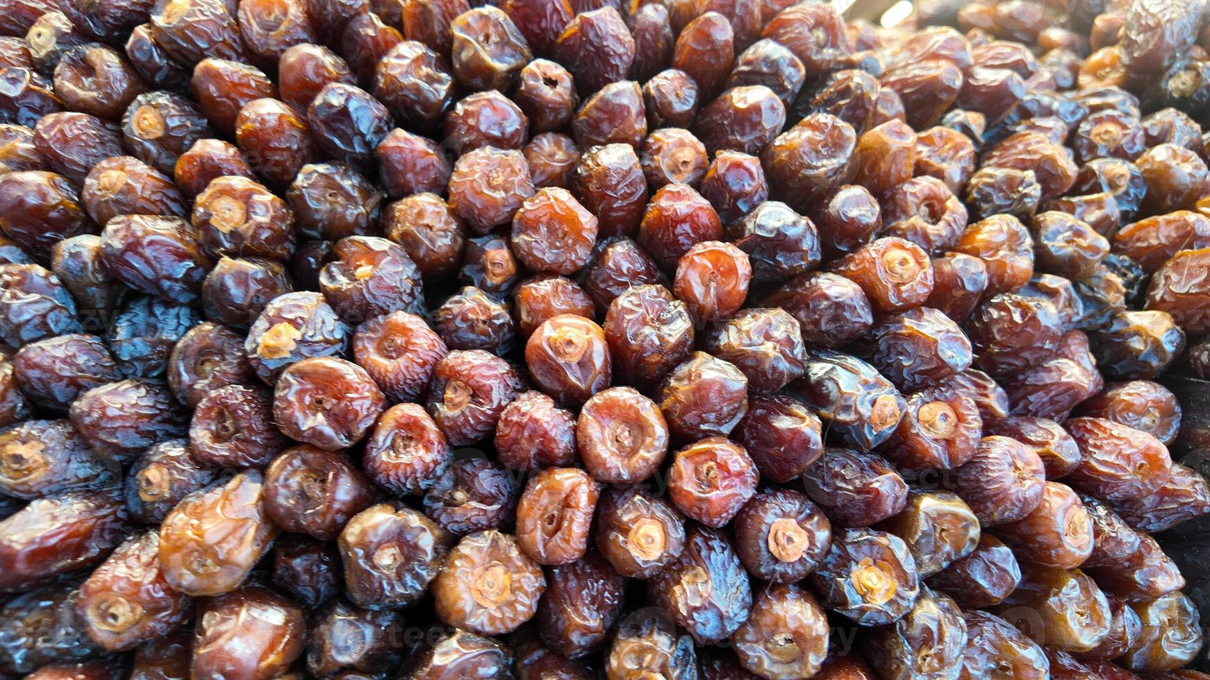Fresh dates piled high at a market in a sunny location photo