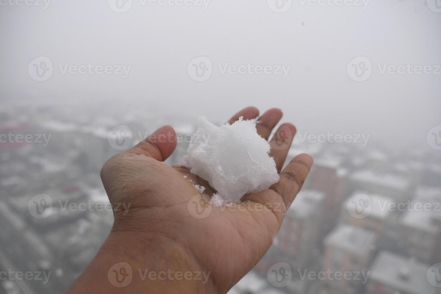 Snow held in a hand against a foggy city backdrop photo