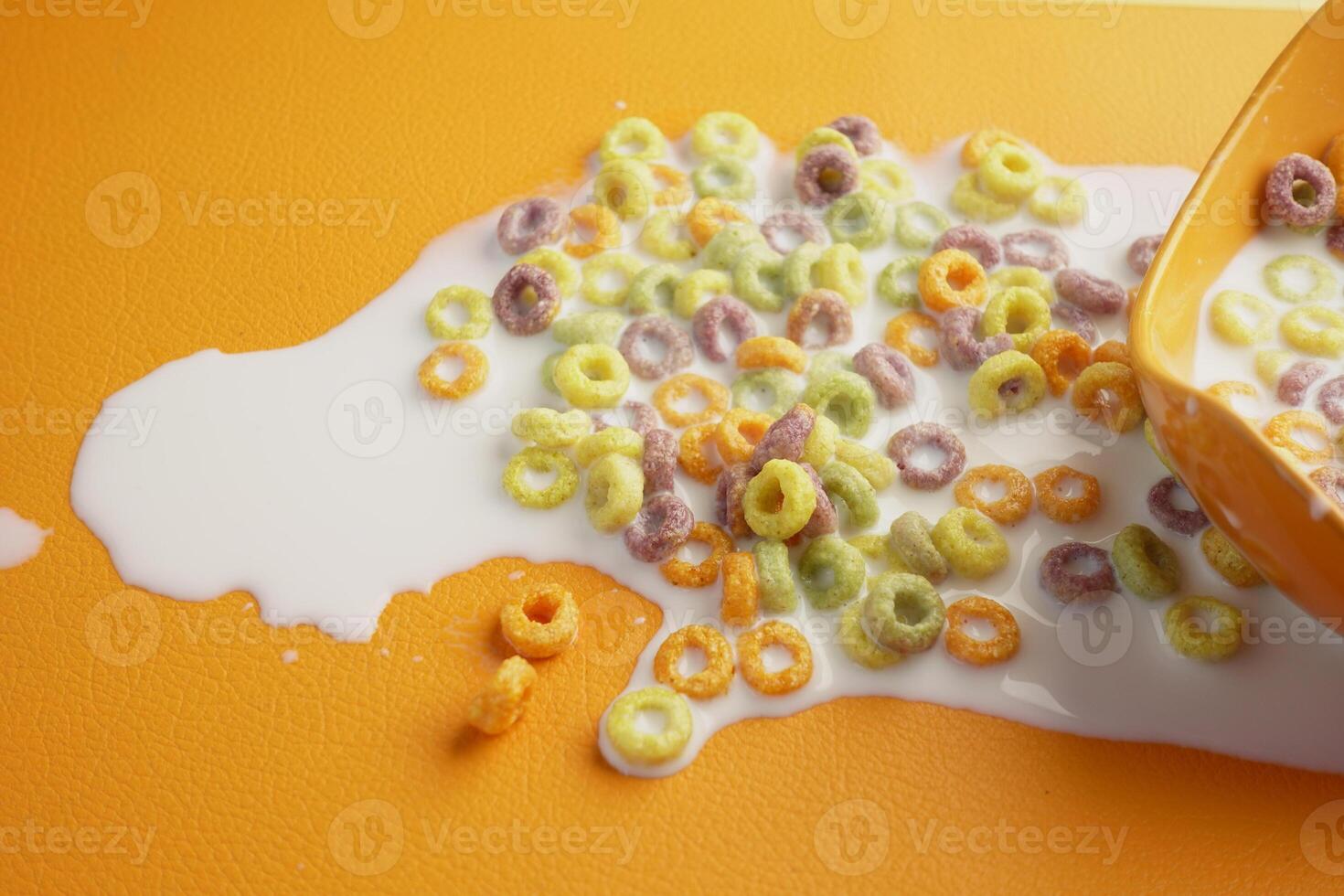 Cereal and milk spilled on a bright orange surface during breakfast photo