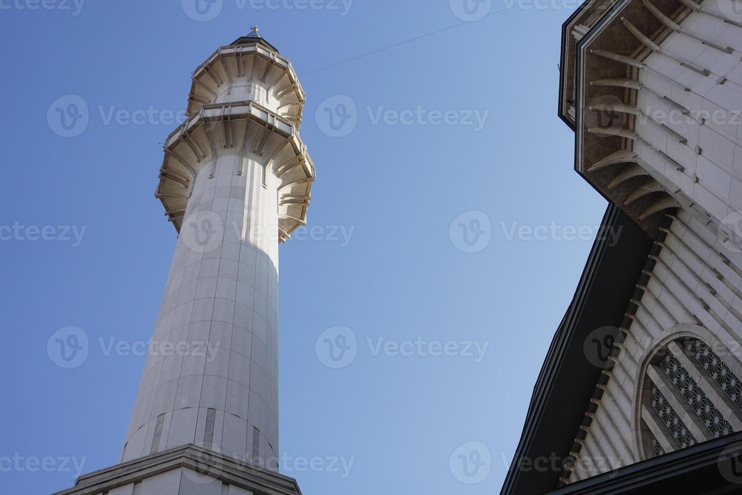 Tall minaret rising against clear blue sky in historic location photo