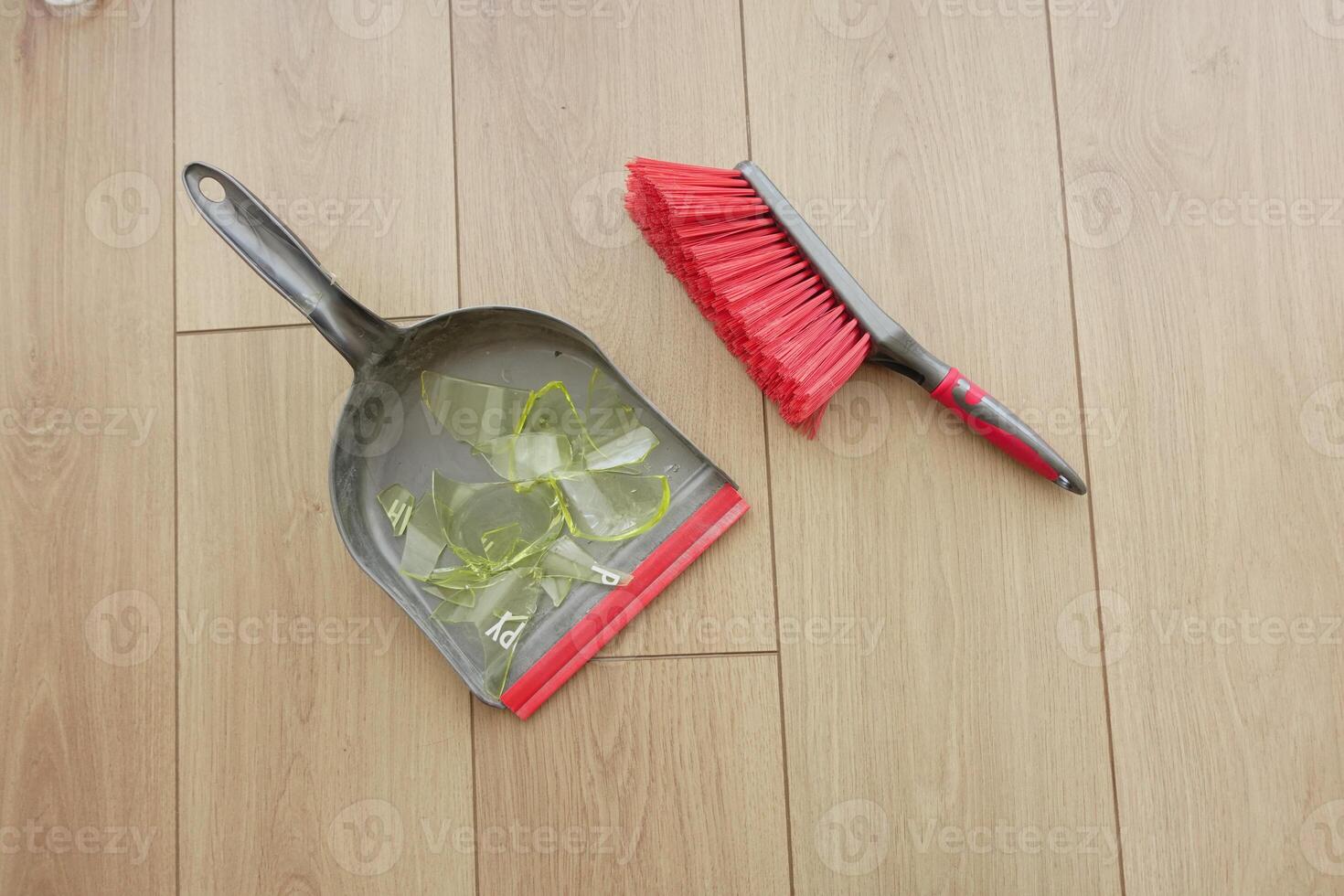 Cleaning up broken glass on wooden floor with a dustpan and brush photo