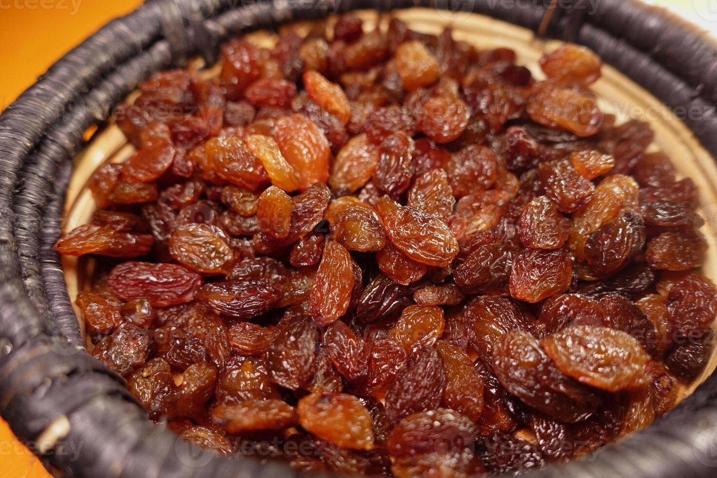 Freshly harvested dark raisins in a wicker basket ready for use photo