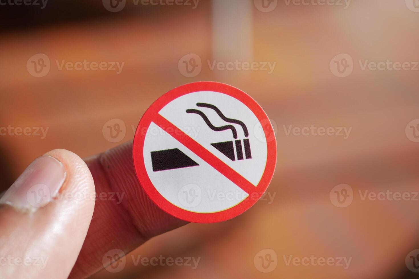 No smoking sign held in hand with wooden background visible photo