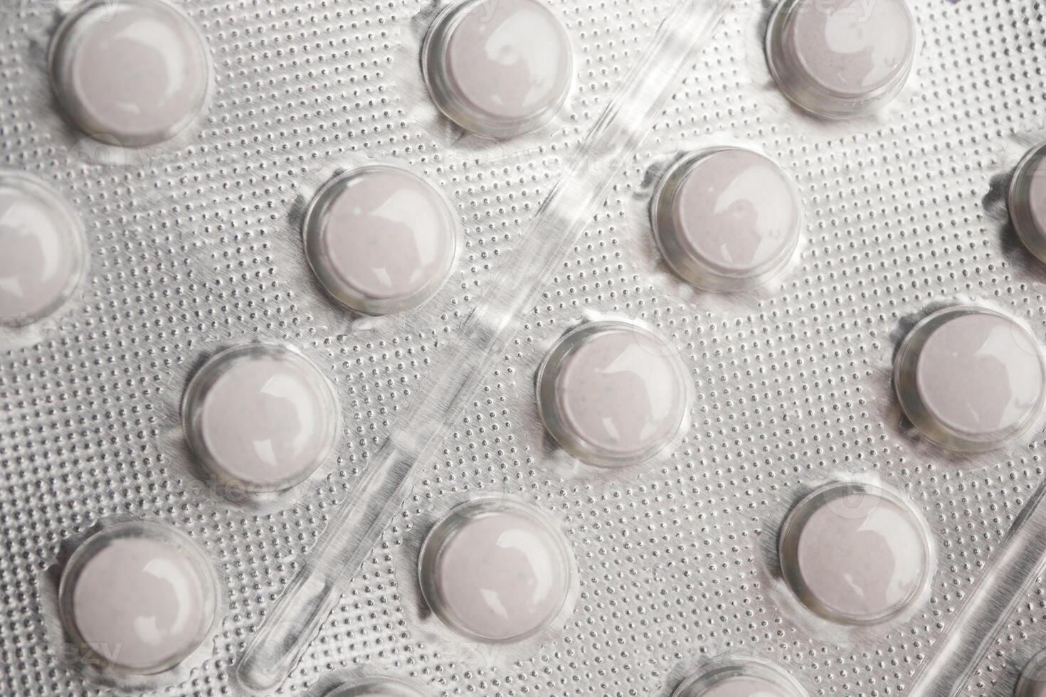 Pills arranged in a blister pack on a textured surface photo
