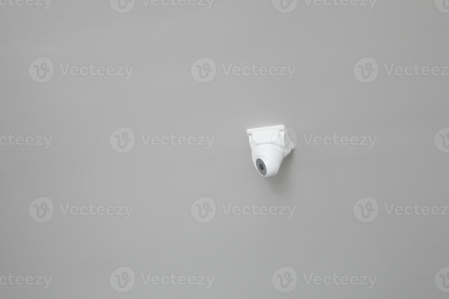 Security camera mounted on a plain gray wall for surveillance photo