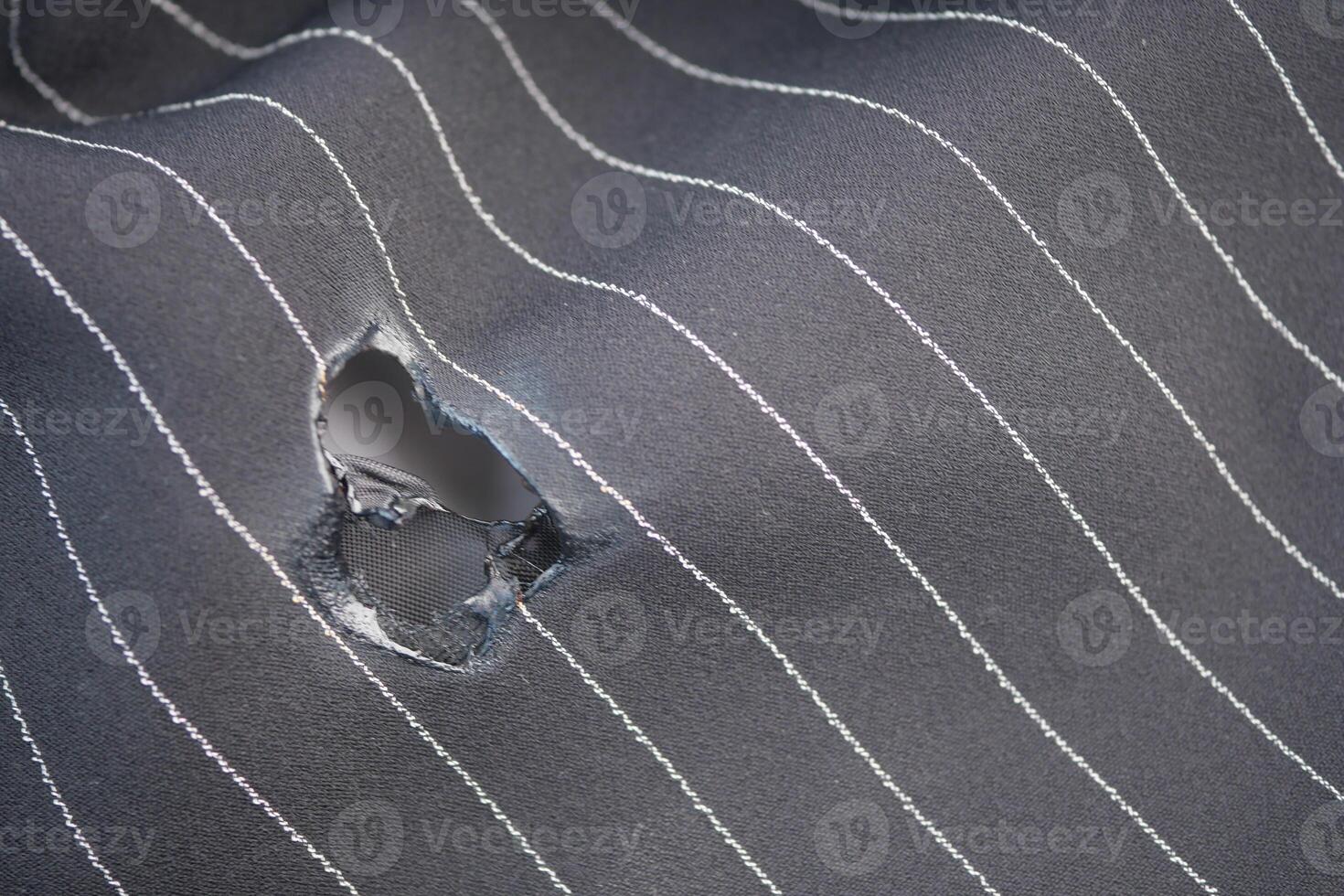 Torn fabric with pinstripes revealing a damaged area during use photo
