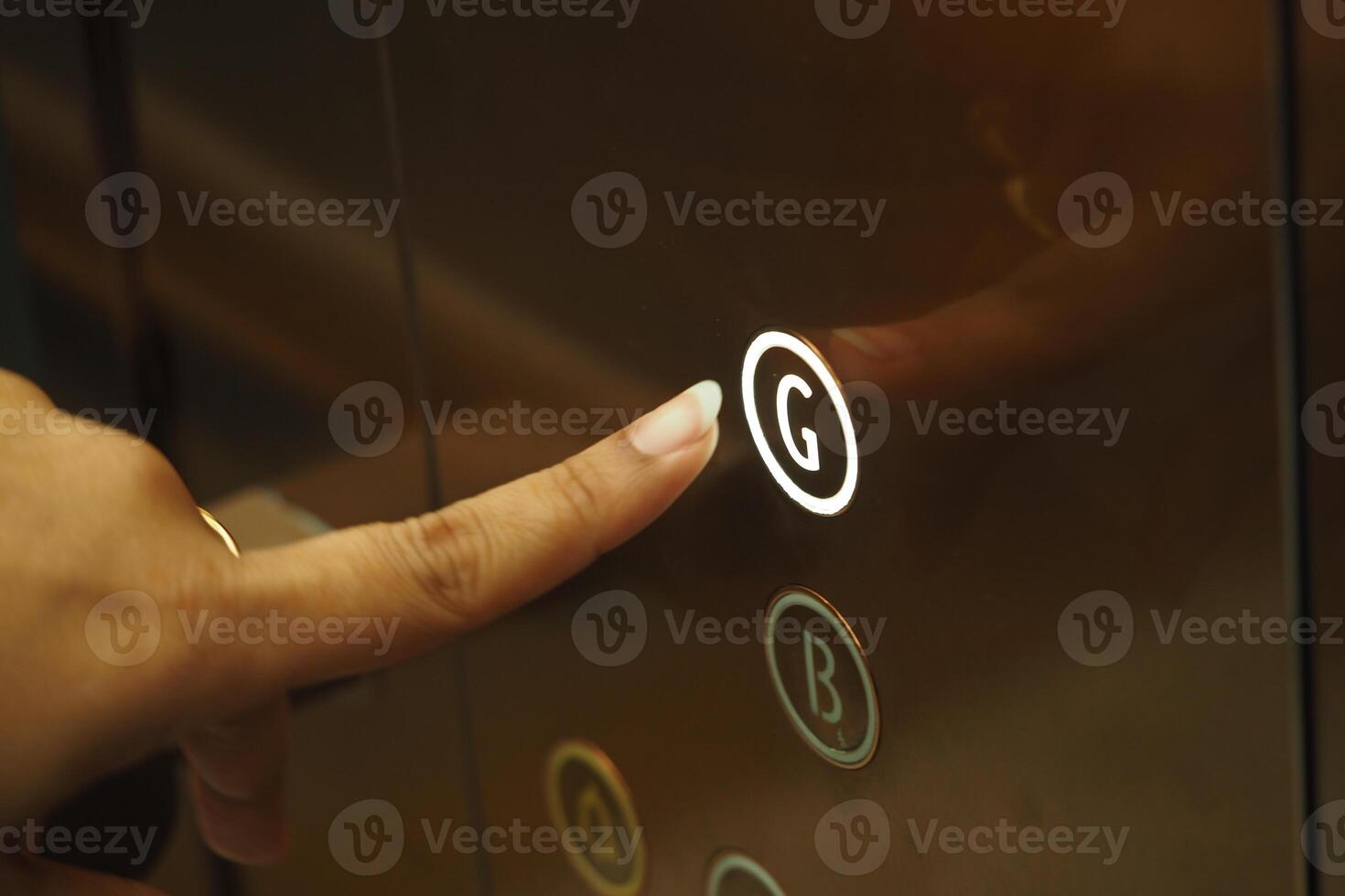 Finger pressing the elevator button for ground floor access photo